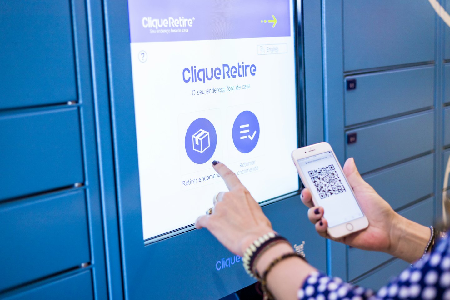 Person scans QR code on phone at blue parcel locker.